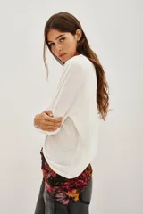 Remera de manga larga en color blanco, confeccionada en una mezcla de lino y viscosa. Presenta un escote en V con detalle de solapa y puños rectos.