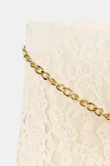 Falda midi color crema o blanco roto, confeccionada en tejido de encaje con forro interior a tono. Presenta cintura elástica y se complementa con un cinturón tipo cadena metálica dorada con caída.