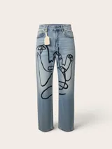 Jean de corte wide leg en denim azul claro, intervenido a mano con ilustraciones abstractas de rostros en líneas color rosa y blanco. Presenta tiro medio-alto y diseño de cinco bolsillos.
