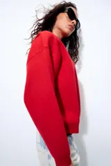 Sudadera de punto lisa en color rojo, con cuello subido y manga larga. Presenta un diseño de corte holgado con acabados en rib en puños y ruedo.
