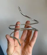 Brazalete rígido en forma de espiral de metal plateado.