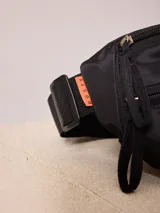 Riñonera negra marca Rusty con logo blanco estampado en el frente.