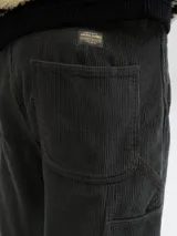 Pantalón de tiro alto y corte wide leg, confeccionado en tejido de corderoy. Presenta bolsillos laterales y traseros, con cierre frontal de cremallera y botón.