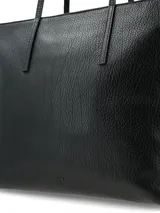 Cartera shopper de gran tamaño, confeccionada en cuero graneado negro, con cierre principal, asas finas y bolsillos interiores.