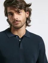 Remera tipo polo de tejido de punto con textura, color azul petróleo, de manga larga y cierre frontal con botones.