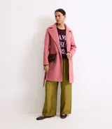 Saco largo de polivelour color rosado, con solapas clásicas, cierre frontal cruzado y cinturón de la misma tela con trabillas laterales. Cuenta con mangas largas y forro interior.