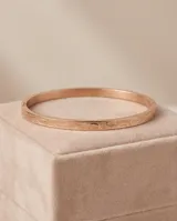 Esclava rígida de acero con baño de oro rosa, presenta un diseño grabado sutil en toda su superficie.