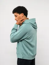 Canguro de felpa color verde menta, con capucha, bolsillo canguro frontal y etiqueta del logo Umbro en la parte delantera.