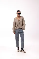 Saco tejido de punto color azul, con escote en V y cierre frontal mediante lazos. Presenta mangas largas amplias con puños ajustados y un calce relajado.