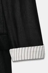 Blazer de lino color verde militar, con cuello solapa, hombreras y manga larga con puño revuelto con detalle a rayas. Cuenta con cierre frontal de un botón y bolsillos delanteros con solapa.