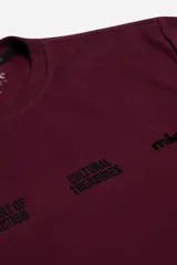 Remera de algodón con trama visible, color bordó, de corte regular y estructura firme. Presenta estampa frontal en relieve con texto.