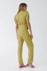 Mono negro de lino con escote pronunciado en V y nudo frontal que deja ver un corte en la cintura. Mangas cortas abullonadas y pantalón de corte recto.