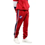Pantalón de jogging bordó con franjas laterales en azul marino y blanco. Presenta el escudo del Club Nacional de Football en el muslo, cintura elástica con cordón ajustable y puños en los tobillos.