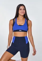 Conjunto deportivo compuesto por un top de escote redondo con espalda estilo nadador y un short de tiro alto. Ambas piezas presentan un diseño bicolor en azul eléctrico y azul marino, confeccionadas en tejido acanalado con el logo de la marca estampado en el frente del top.