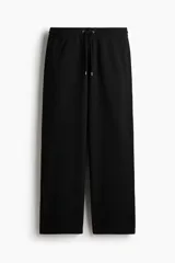 Pantalón de jogging negro de felpa pesada, corte holgado con cintura elástica ajustable mediante cordón y bolsillos laterales.