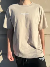 Remera de corte semi oversize en color beige, con cuello redondo y estampa pequeña en el pecho.
