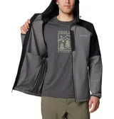 Campera softshell con capucha, de diseño bicolor en gris y negro. Cuenta con cierre frontal completo, bolsillo vertical en el pecho con cierre y bolsillos laterales. Presenta logo de la marca estampado en el pecho y puños elásticos.