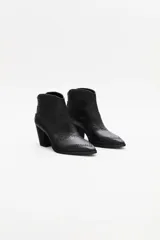 Bota corta estilo western de cuero vacuno negro, con puntera fina y detalles de textura grabada tipo reptil. Presenta costuras decorativas y apliques de tachas metálicas pequeñas en el diseño. Cuenta con taco cuadrado y cierre lateral.
