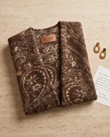 Poncho marrón con diseño estampado y detalles de flecos en el ruedo inferior.