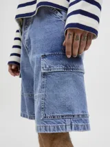 Bermuda cargo de jean baggy fit con tiro alto, múltiples bolsillos y pernera amplia. Presenta un acabado stonewash con efecto desgastado.