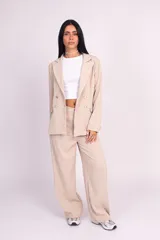 Blazer de corte levemente largo y diseño de doble botonadura, color beige, con solapas de muesca, hombreras y bolsillos delanteros con solapa.
