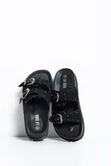 Sandalia negra con plataforma y suela track. Posee dos tiras anchas en el empeine con hebillas metálicas plateadas de estilo western, detalles de tachas y plantillas anatómicas.