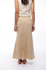 Falda larga de jean color beige, corte recto con vuelo en el ruedo y costuras verticales a lo largo de la prenda.
