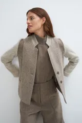 Chaqueta corta color beige con cuello solapa y diseño con patchwork de telas. Manga larga con detalle de coderas aplicadas. Cierre frontal mediante botones. Bolsillos ojal. Con forro. Tela 100% lana fina sin teñir, diseñada exclusivamente por Don Baez. Hecha 100% en Uruguay.