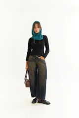 Top de manga larga color marrón, confeccionado en tejido acanalado con cuello bote. Presenta costuras decorativas expuestas a lo largo de las mangas, creando un efecto de relieve.