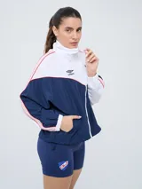 Campera deportiva Umbro del Club Nacional de Football, modelo Sky para mujer. Diseño en tonos azul marino y celeste con detalles en blanco y líneas finas rosadas, cuello alto, cierre frontal y bolsillos.