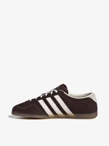 Championes Adidas Gazelle Lo Pro, modelo de corte bajo confeccionado en gamuza marrón con las tres tiras características en blanco, cordones blancos y suela de goma translúcida.