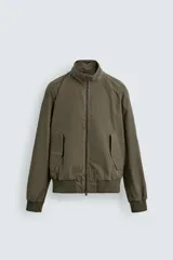 Cazadora de corte relajado color verde militar, con cuello subido, cierre frontal con cremallera y bolsillos laterales con solapa. Presenta puños y ruedo con acabado en rib.