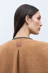 Capa color tostado con vivos en contraste de color negro, cierre frontal con un botón grande y un bolsillo lateral.