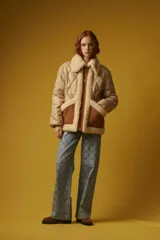 Campera puffer color beige con diseño acolchado de rombos, cuello y solapa de sherpa color crema, cierre frontal con cremallera dorada, bolsillos laterales con solapa marrón y puños elásticos.