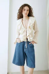 Blusa de voile color beige, de manga larga, con volados en el escote en V y tirantes frontales para atar.
