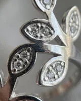 Anillo de acero quirúrgico de diseño abierto con forma de ramas con hojas pavimentadas con circonitas.