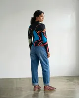 Remera de manga larga con estampa abstracta y orgánica que combina tonos verde, turquesa, magenta, azul y tierra sobre base negra. Presenta cuello redondo y silueta ajustada.