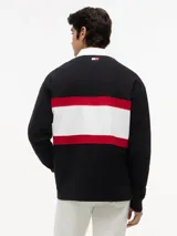 Chomba de rugby de manga larga Tommy Hilfiger en colaboración con Cadillac Formula 1 Team. Presenta un diseño en bloques de color negro, blanco y rojo, con cuello estilo rugby en color blanco y cierre frontal oculto. Incluye el logo de Cadillac en fuente script y el logo de Tommy Hilfiger estampados en el pecho.