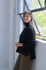 Polerón negro de cuello alto, con diseño de costura vertical central y puños acanalados. Presenta un corte holgado con dobladillo asimétrico, siendo más largo en la parte posterior.