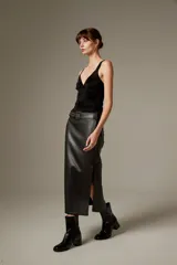 Falda midi de eco-cuero negro con corte recto y tajo lateral, incluye cinturón con hebilla metálica.