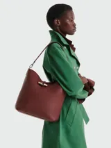 Bolso hobo de hombro Longchamp modelo Le Roseau M, color bordó, confeccionado en cuero con textura granulada. Cuenta con una manija de hombro fina y el distintivo cierre de bambú de metal plateado en la parte frontal.