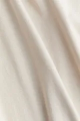 Top de algodón con escote bote, diseño de hombros caídos y mangas largas holgadas.