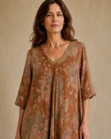 Vestido largo terracota con estampado floral difuminado, escote en V, mangas cortas holgadas y diseño amplio y fluido.