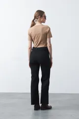 Pantalón de fit recto color beige, confeccionado en cotton spandex. Presenta costuras visibles y bordados decorativos en tono dorado/marrón claro. El ruedo del pantalón tiene un borde festoneado.