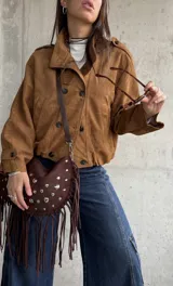 Campera tipo bomber de gamuza color camel, con diseño de doble botonadura frontal, cuello camisero y mangas largas con puños abotonados.