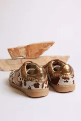 Zapatillas deportivas con estampado animal print de vaca en blanco y negro, con detalles en cuero sintético plateado en los laterales y talón.