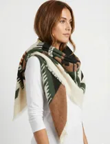 Pashmina cuadrada de gran tamaño con diseño geométrico en tonos verde, marrón, negro y crema, con bordes desflecados.