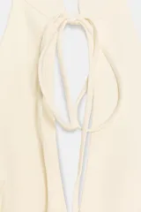 Vestido corto de cuello halter con abertura frontal y lazada, espalda descubierta y falda con bajo acabado en volumen. Incluye cierre de cremallera oculto en la espalda.