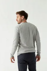 Sweater de punto color rosa con cuello en V y logo bordado en el pecho.