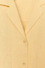Camisa amarilla de lino con cuello solapa, escote pico, manga larga con botones y cierre frontal con botones.